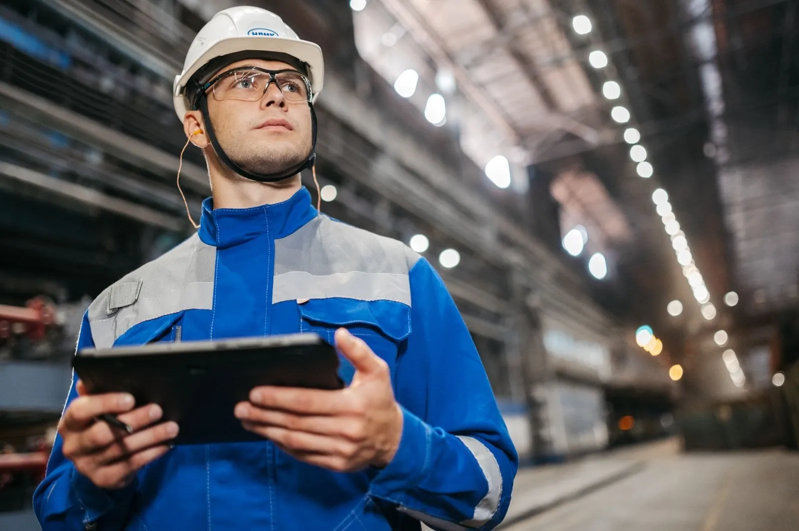 Factory worker in safety gear using a tablet